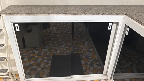 Armário sob bancada de pedra com folhas de correr em vidro fumê, perfis brancos e puxadores embutidos.